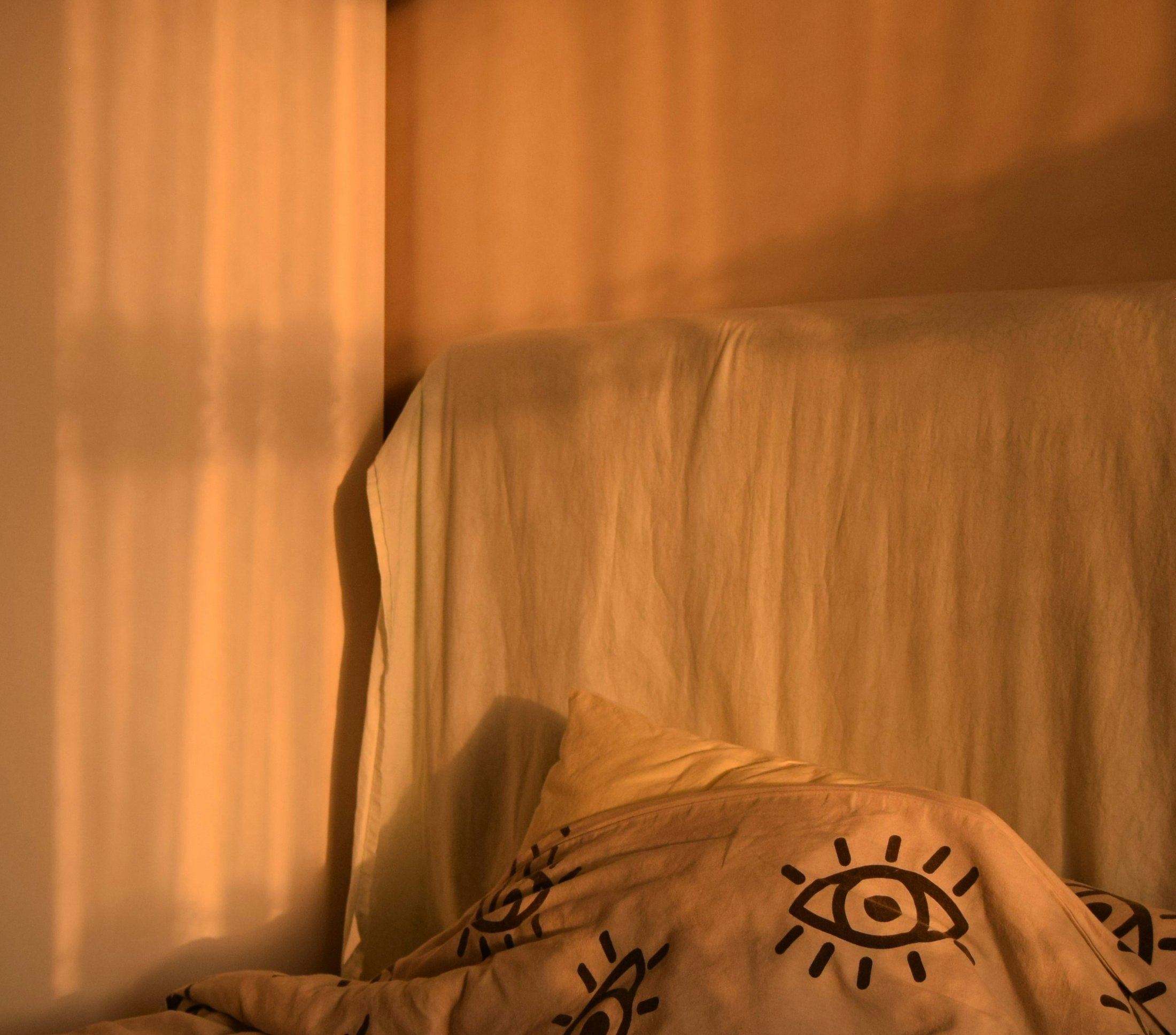 Morning sunlight casting shadows across a neatly made bed