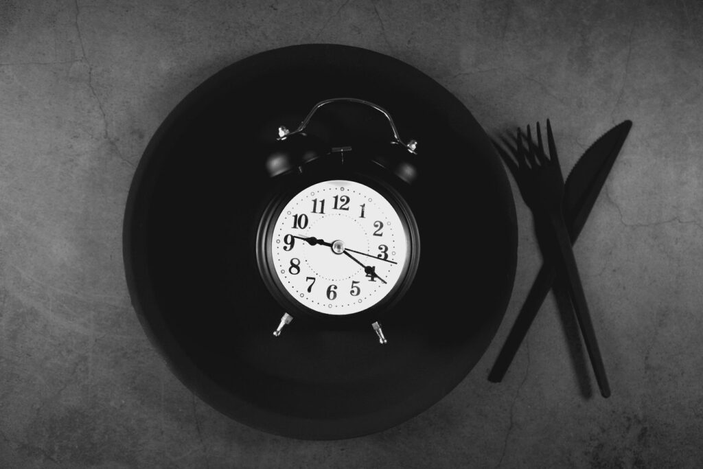 Alarm clock on a plate with cutlery, representing a timed fast