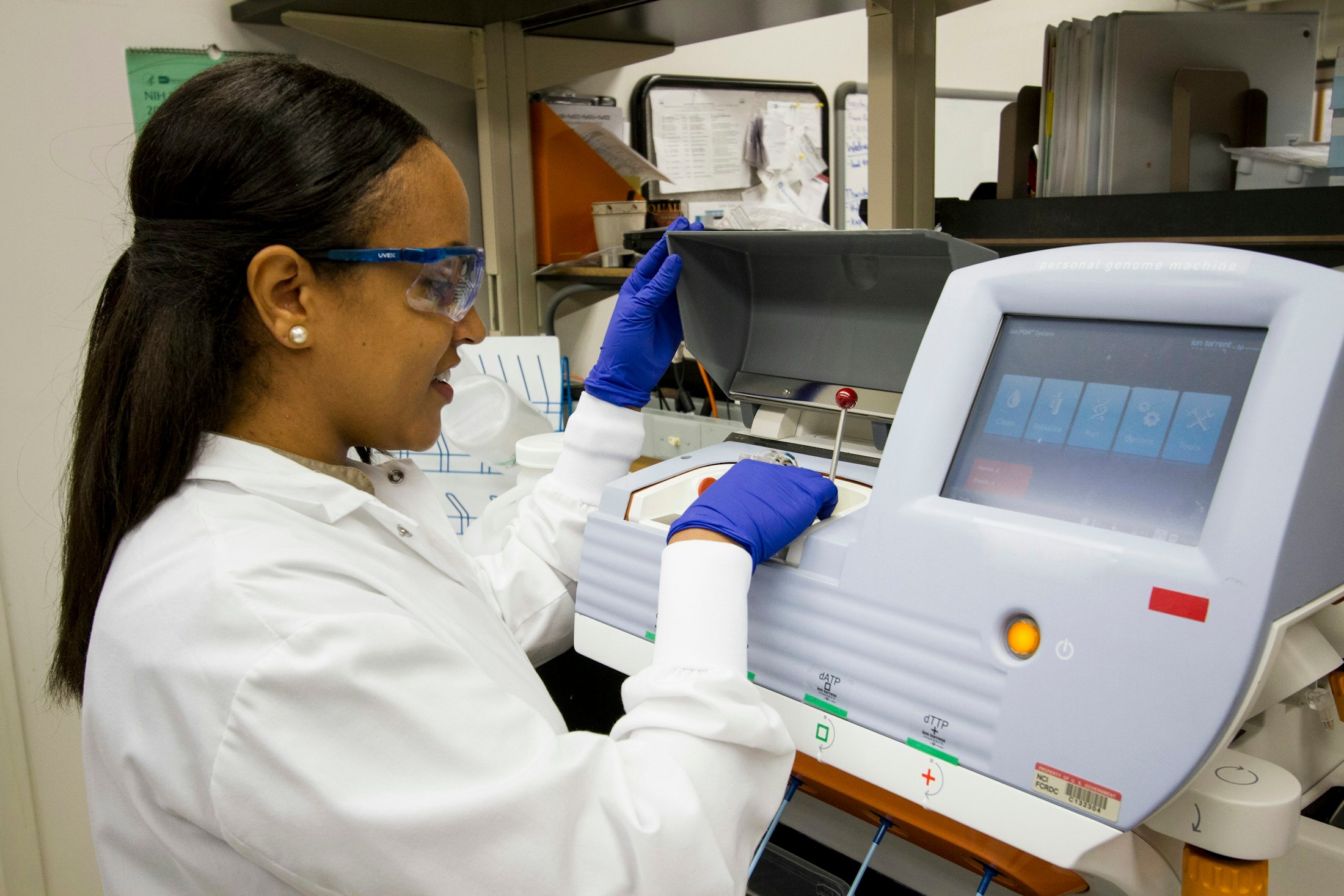 Technician loading DNA samples into a genomic sequencing machine in a laboratory