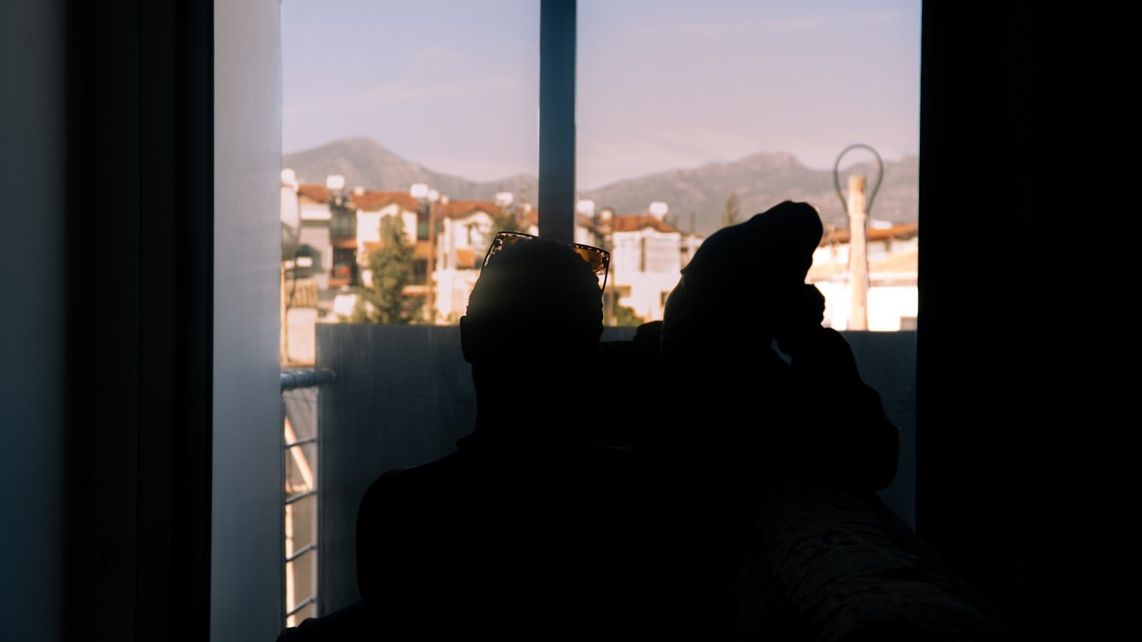Person standing by a window looking out at mountains in a quiet moment