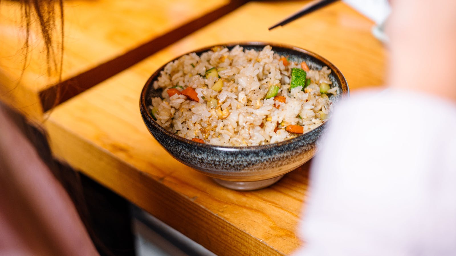 Bowl of rice with vegetables on a wooden table