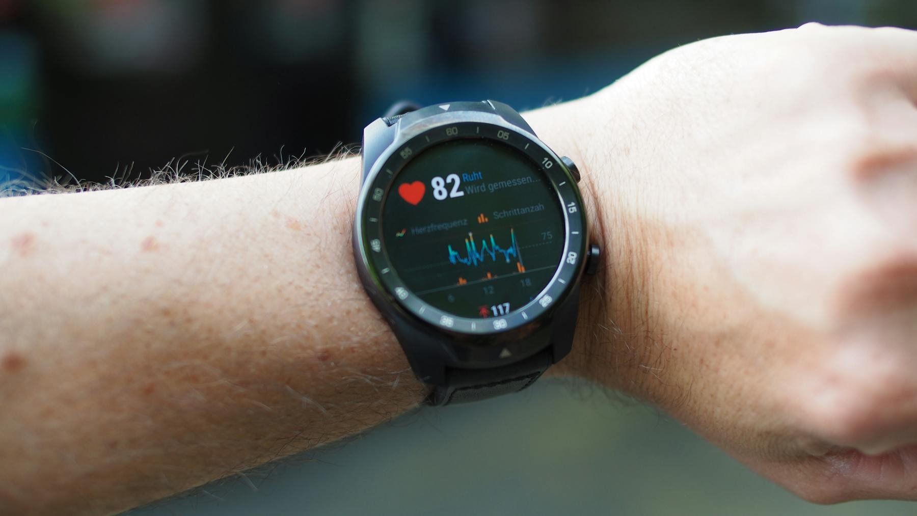 Close-up of a smartwatch showing heart rate data on a wrist outdoors