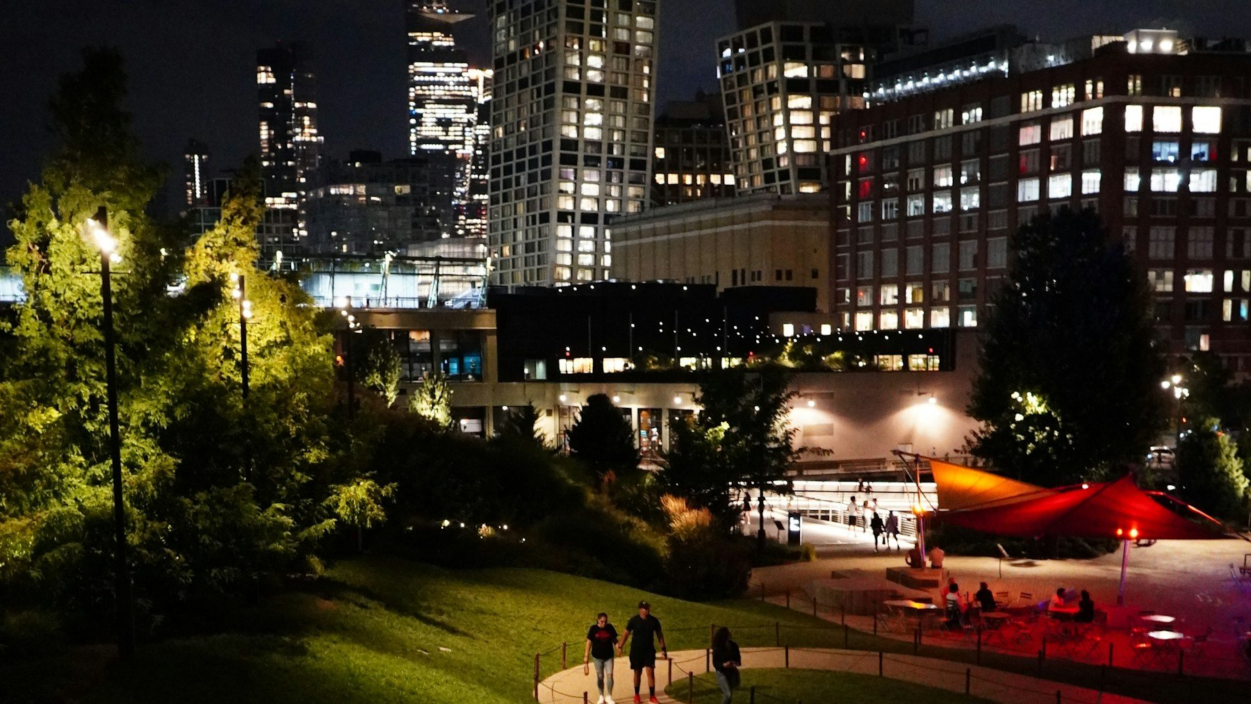 People walking along a softly lit park path in the evening