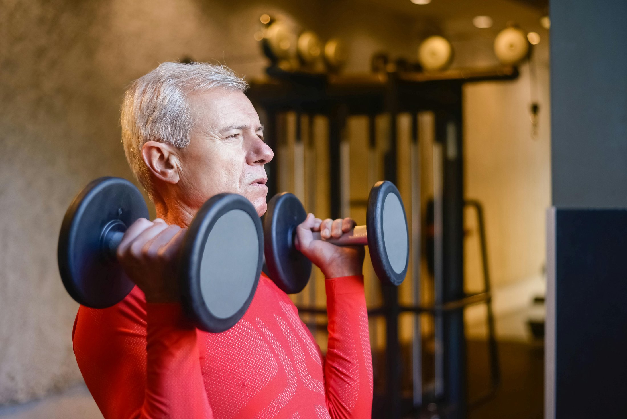 Older adult lifting dumbbells in a gym