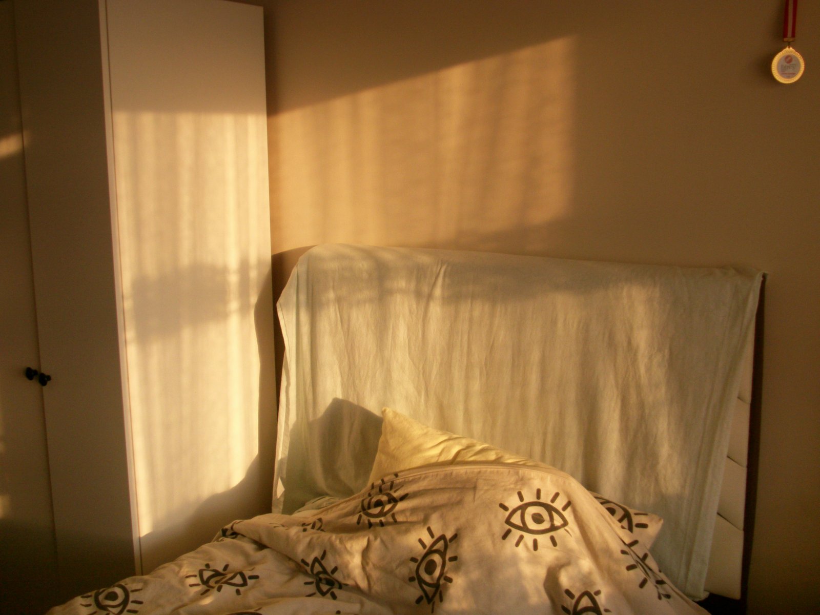 Warm sunlight streams into a quiet bedroom with a bed