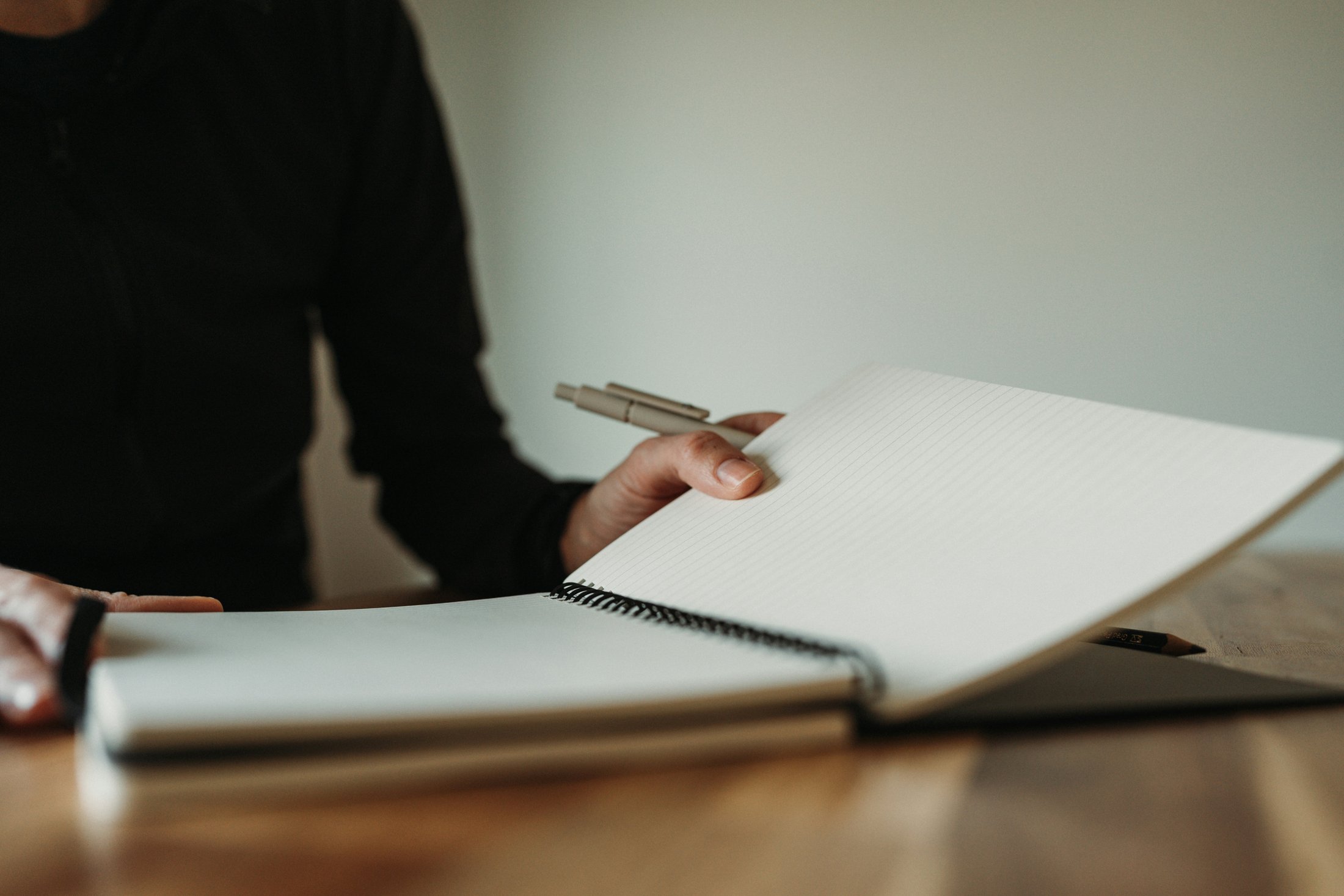 Person holding a pen and writing in a notebook