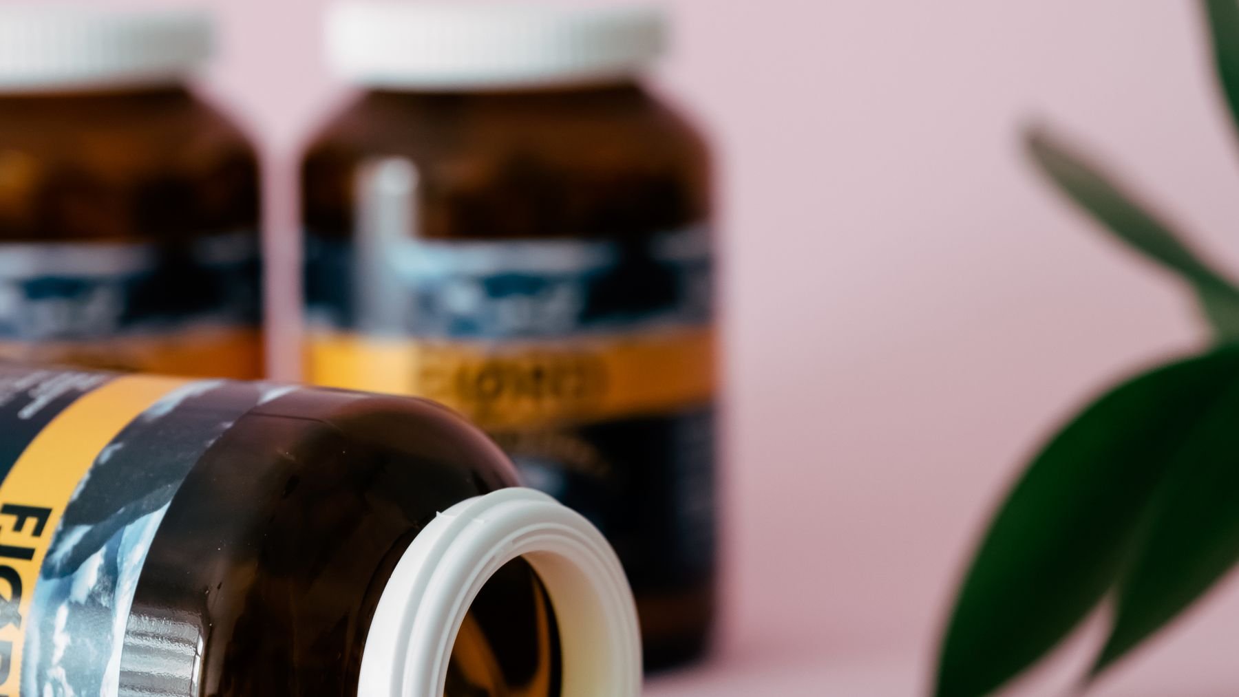 Supplement bottles and capsules on a pink surface