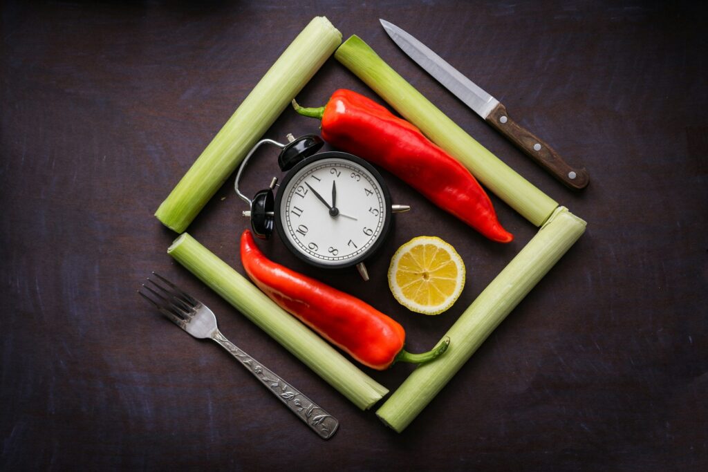 A clock surrounded by vegetables and a knife