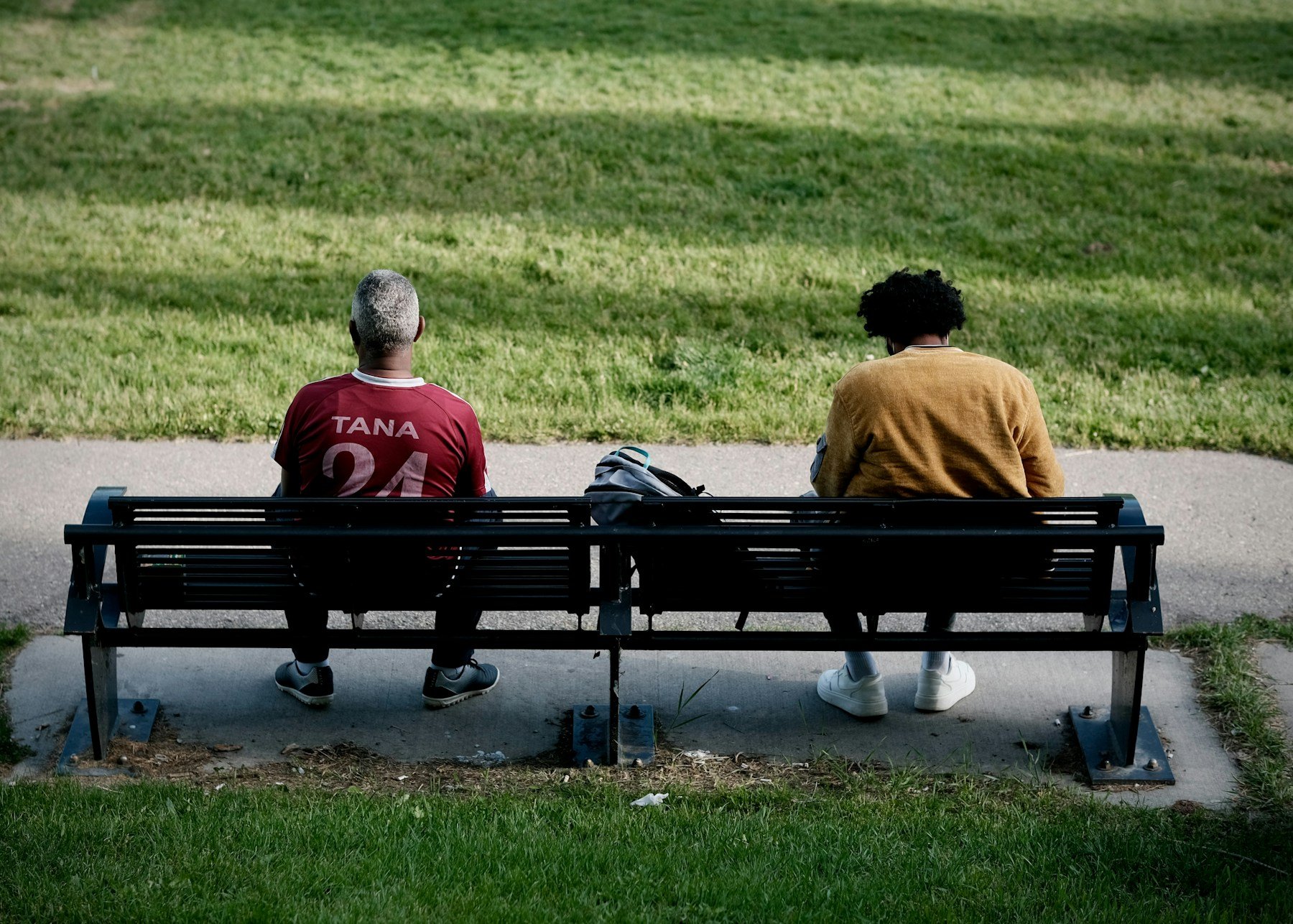 Two people sitting together on a park bench, viewed from behind