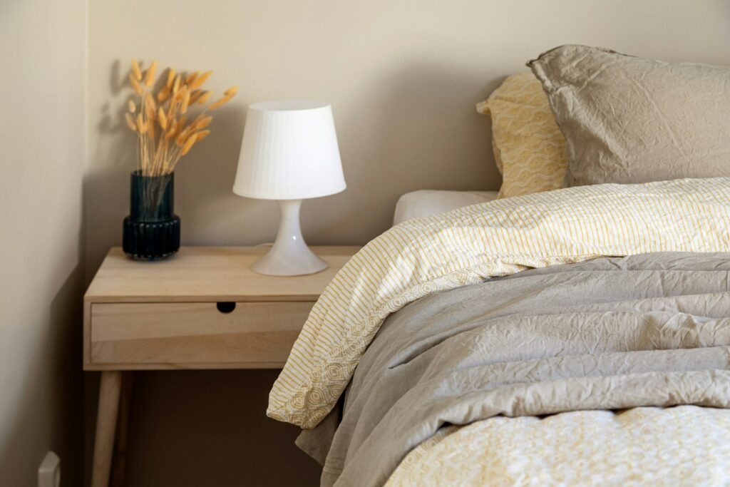 A quiet bedroom with a bed, nightstand, and lamp, used to illustrate sleep timing and melatonin.