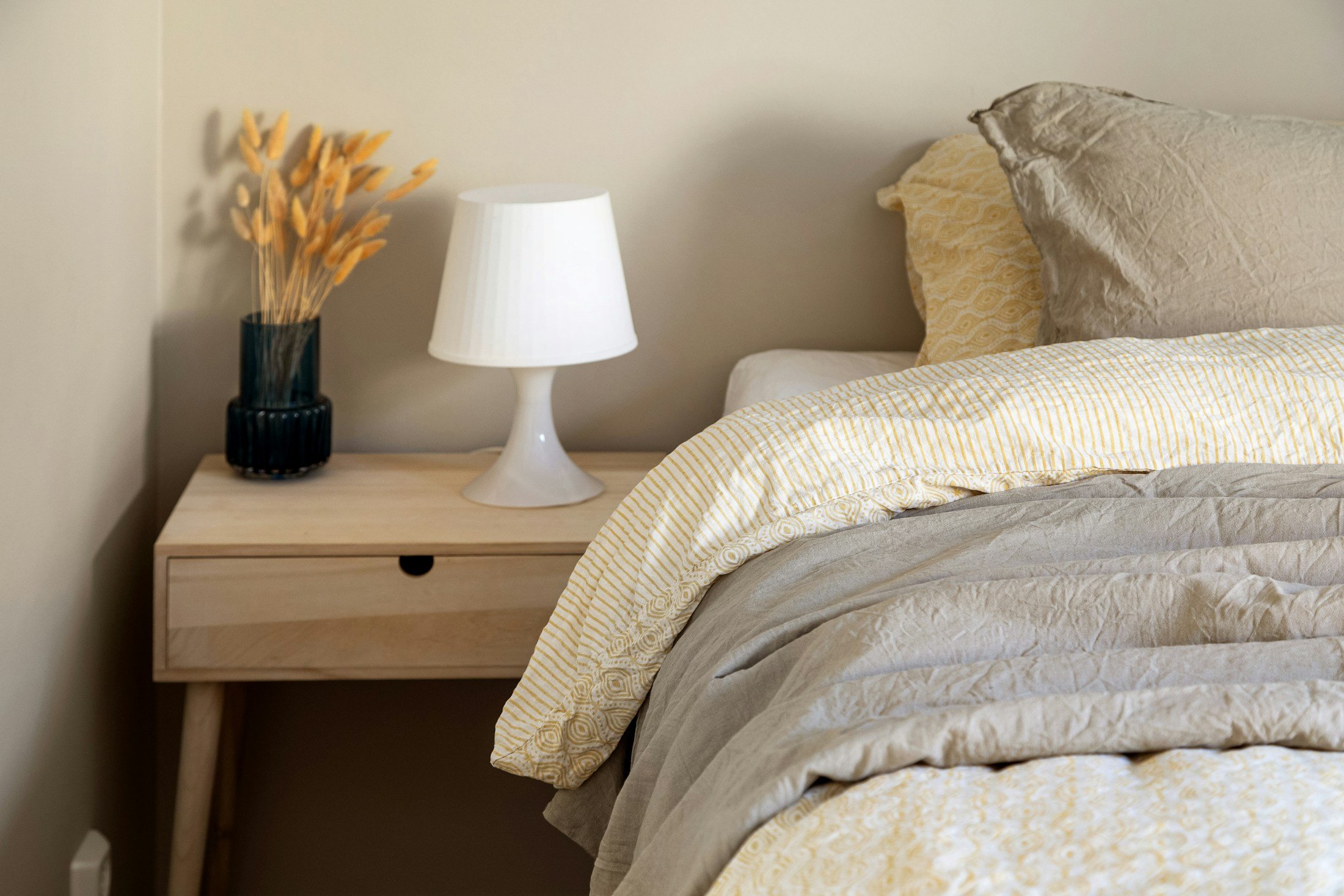 A quiet bedroom with a bed, nightstand, and lamp, used to illustrate sleep timing and melatonin.