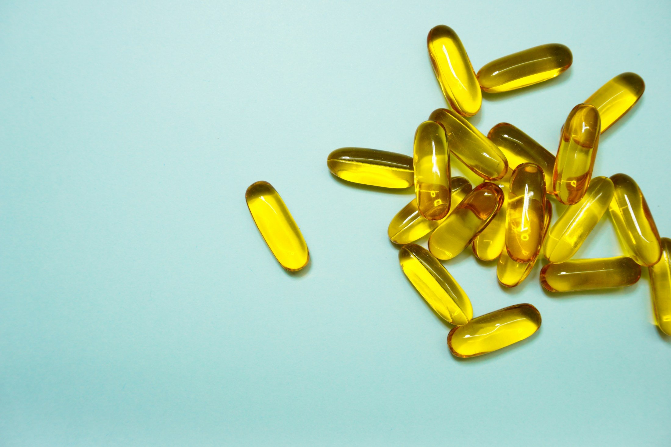 Yellow supplement capsules on a pale blue surface for an article on probiotic supplements