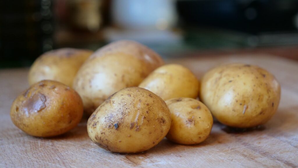 Raw potatoes on a wooden board, representing resistant starch food sources
