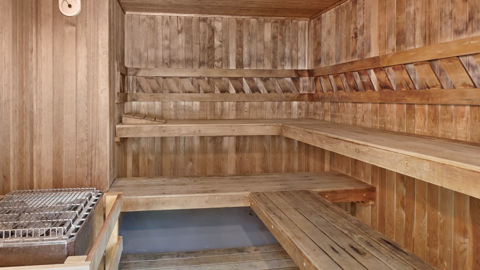 Empty wooden sauna room with benches and a heater