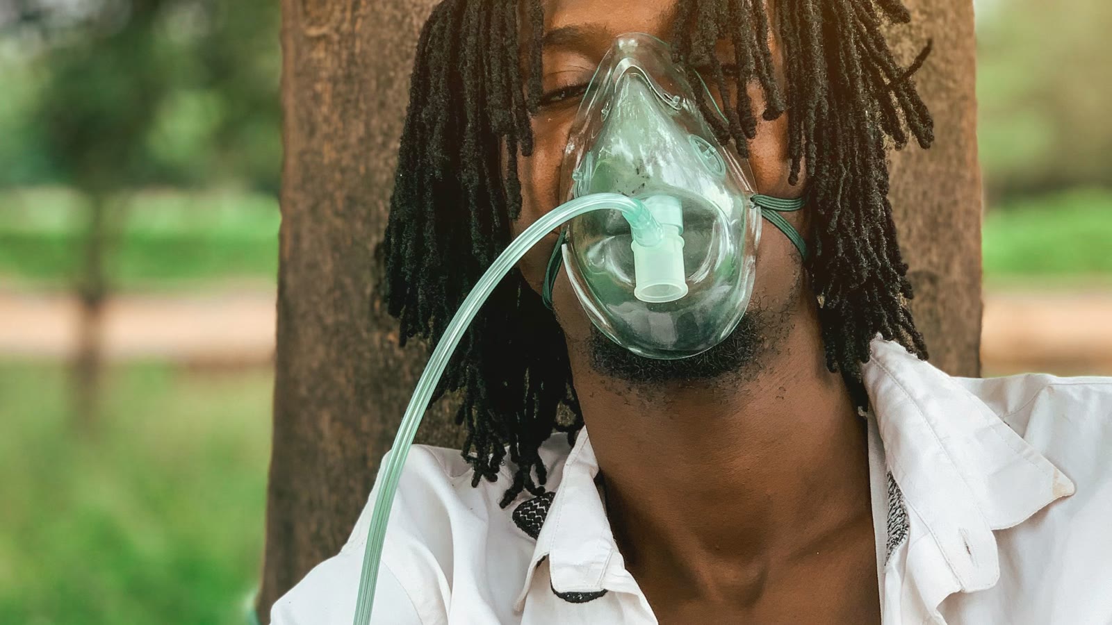 Man resting outdoors while wearing a breathing mask