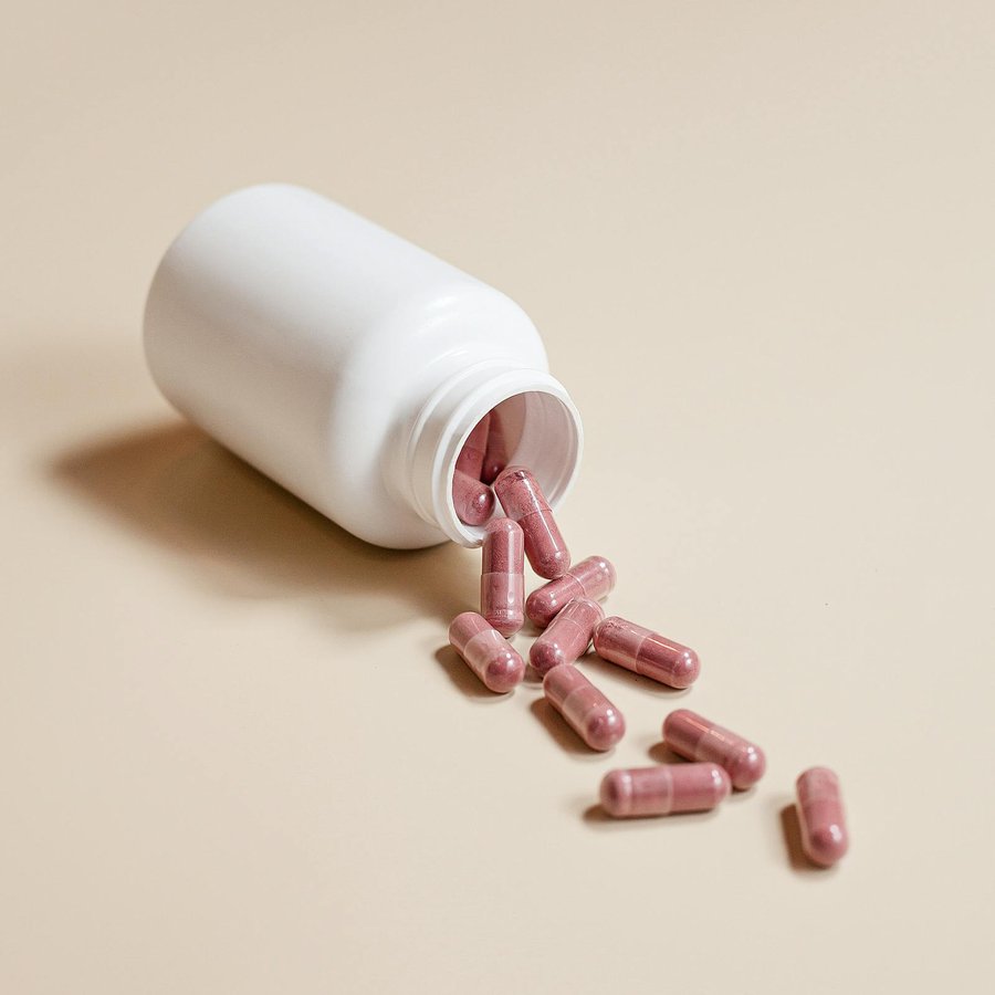 A plain white supplement bottle with capsules on a neutral surface