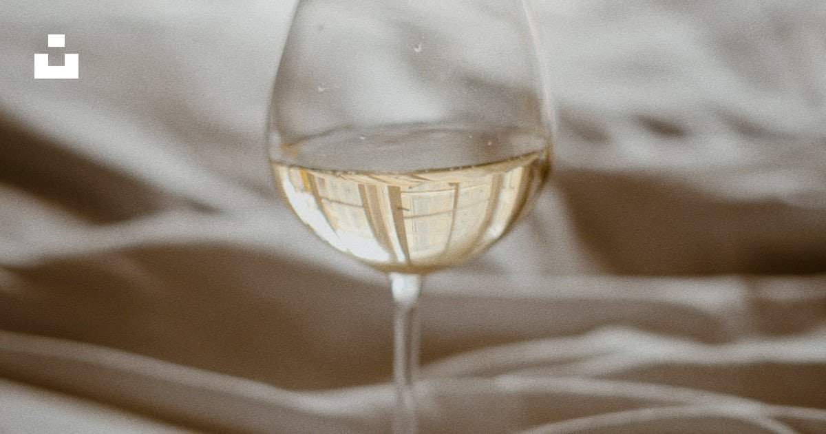 A glass of wine on a bed with soft linen