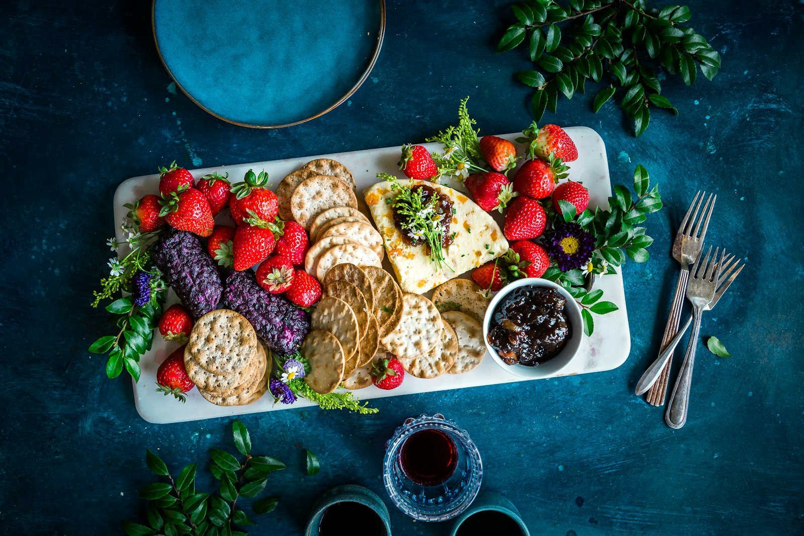 A platter of berries, fruit, and crackers on a table