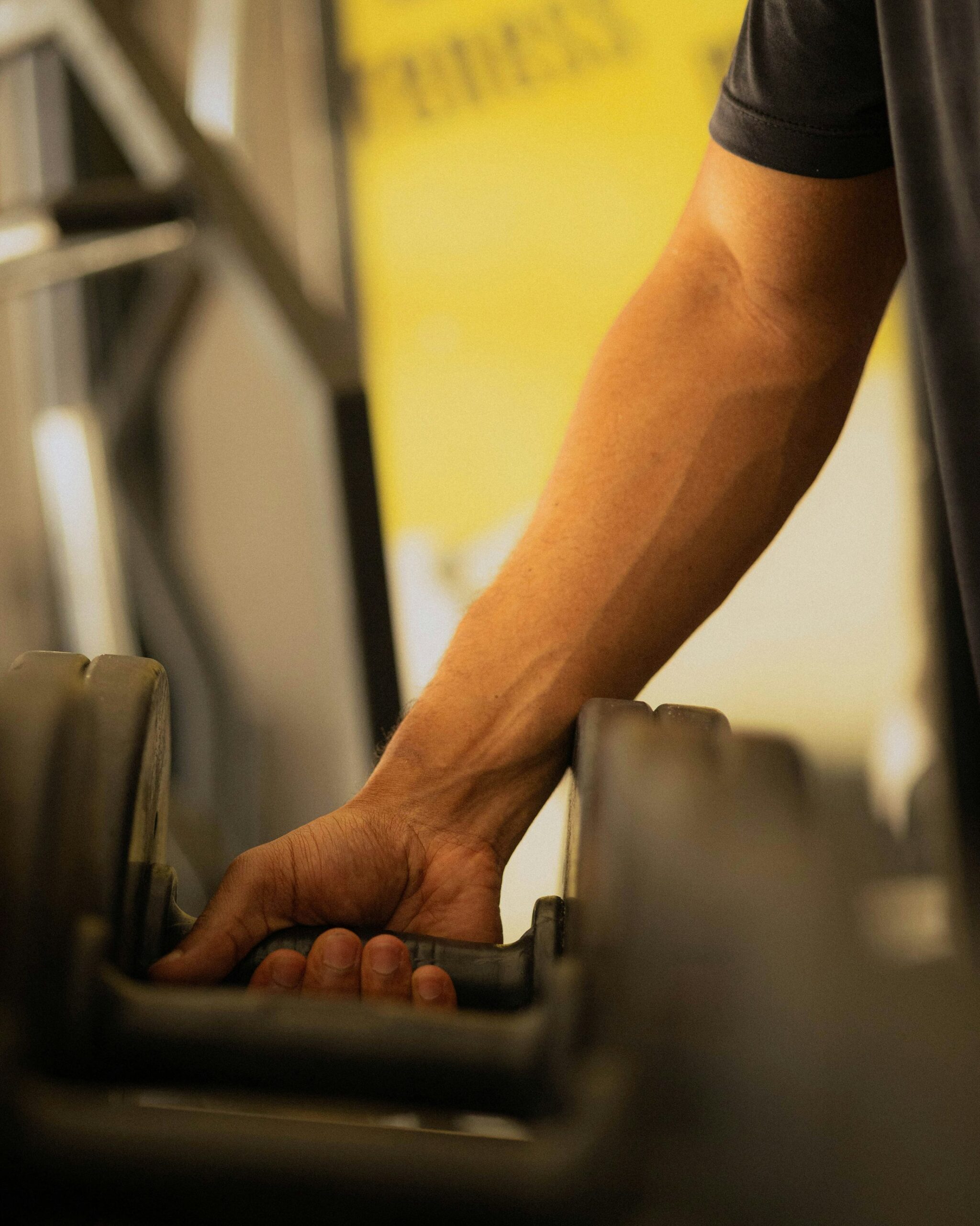 A hand reaching for a dumbbell in a gym