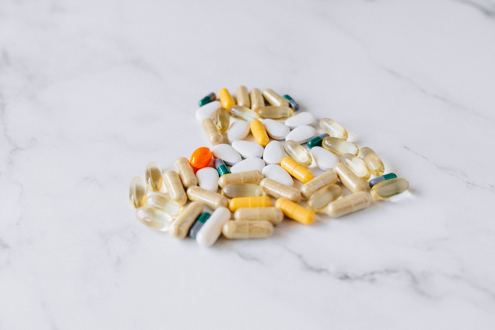 Various supplement capsules and tablets on a marble surface