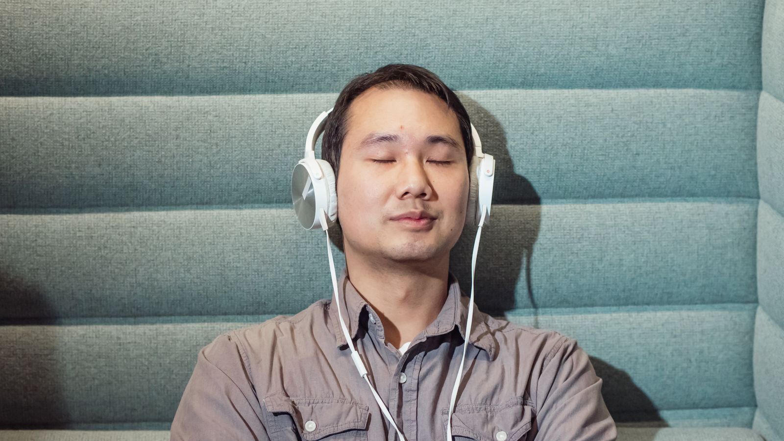 Person wearing headphones while listening to music indoors