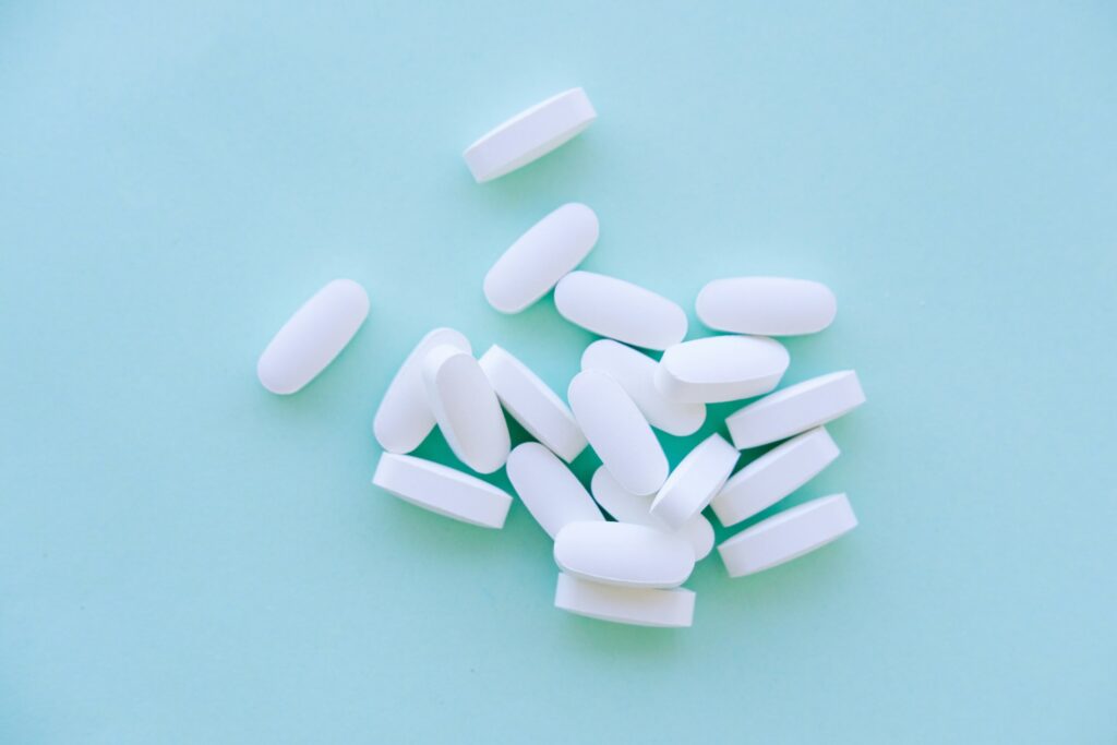White supplement tablets scattered on a blue surface