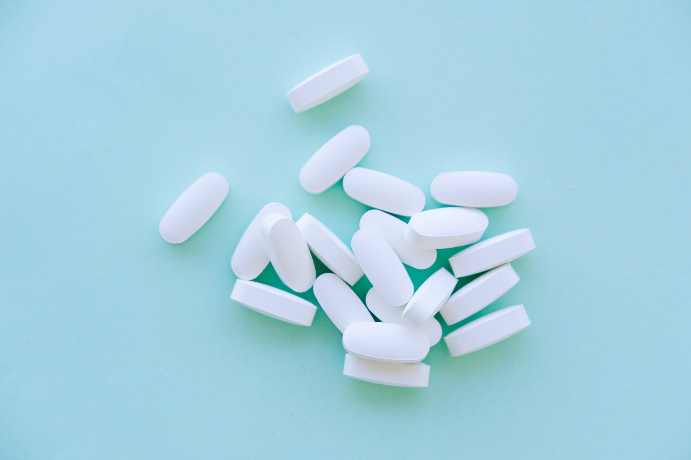 White supplement tablets scattered on a blue surface