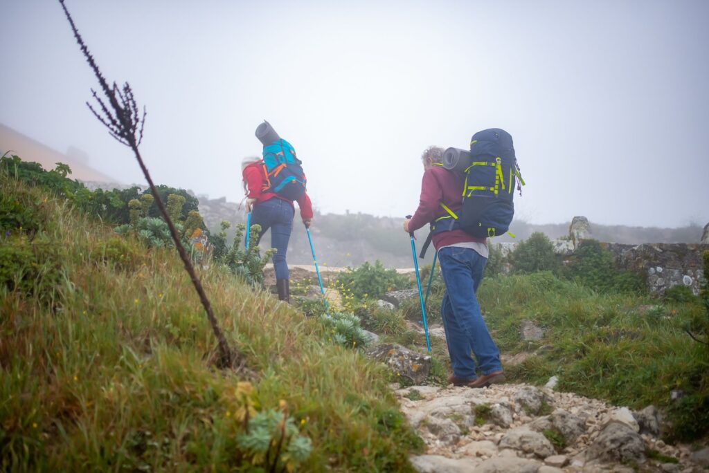 Older couple hiking with walking poles on a misty trail