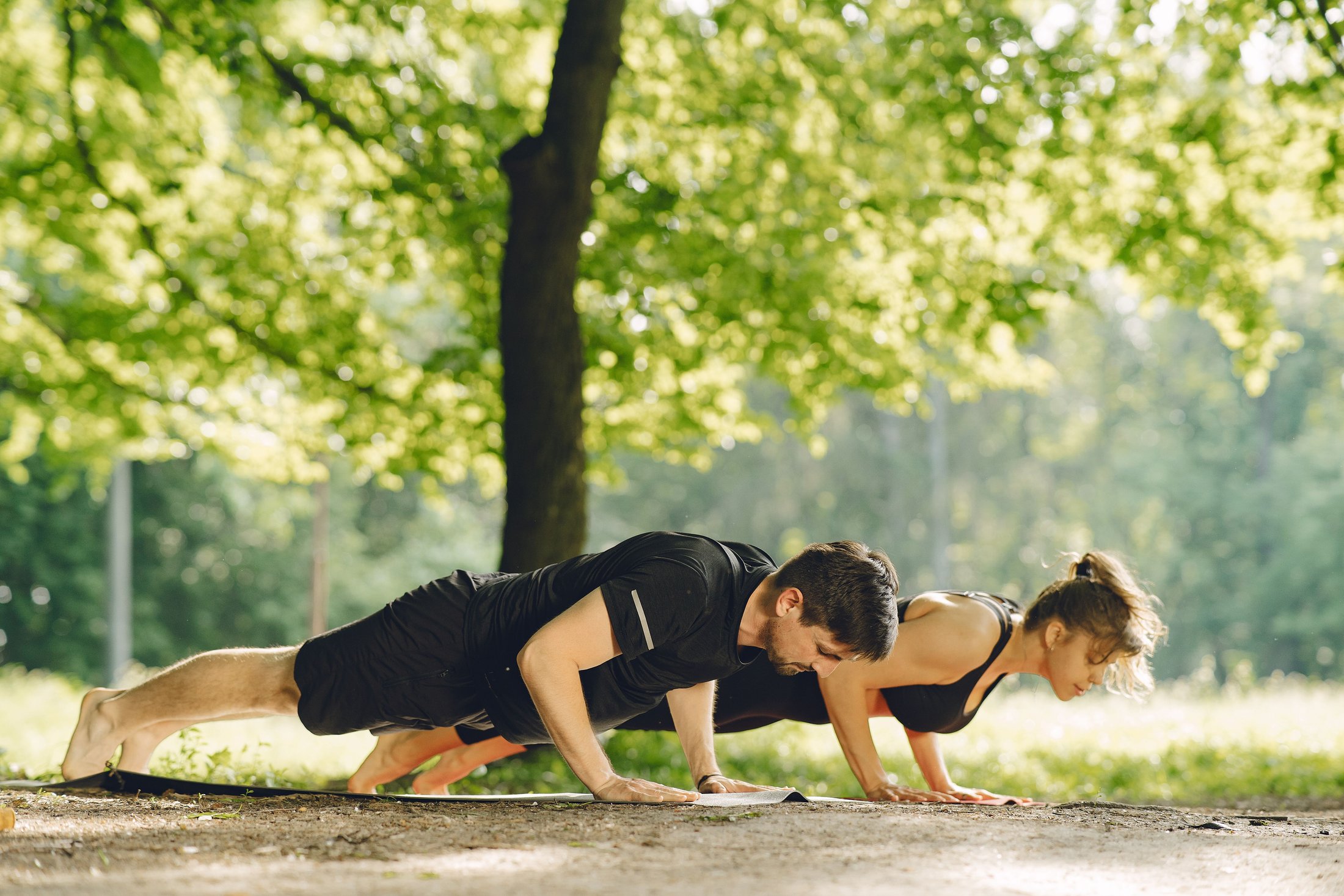 A woman and man doing push-ups on a mat during a workout