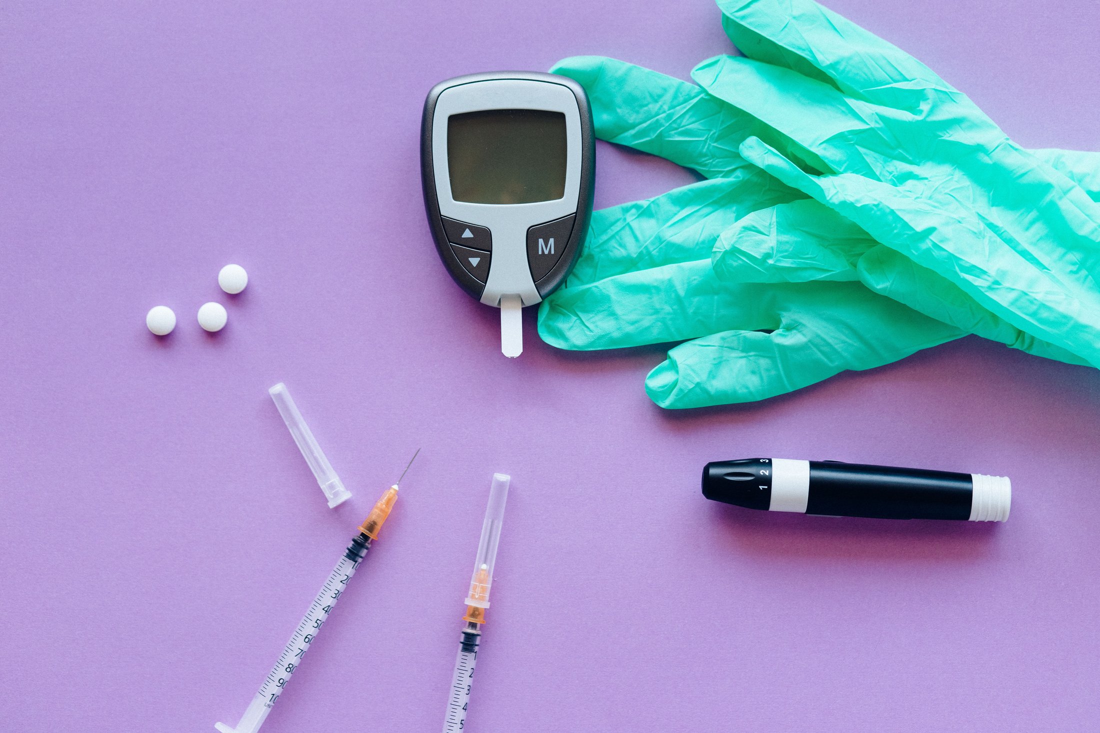 Black and white click pen beside pink textile, representing HbA1c blood testing