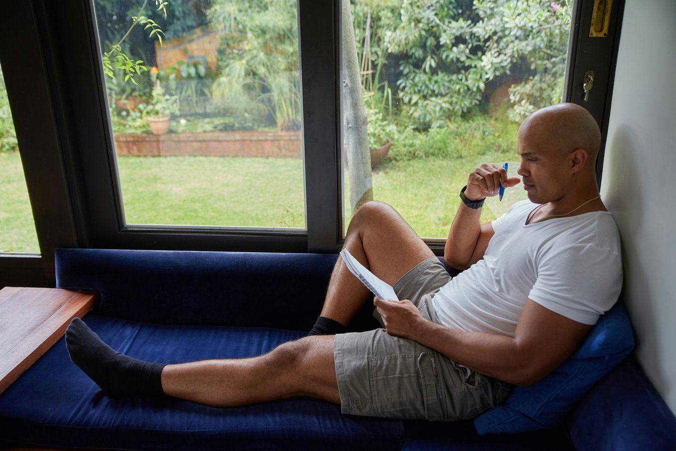 A man sitting on a blue couch looking out of a window