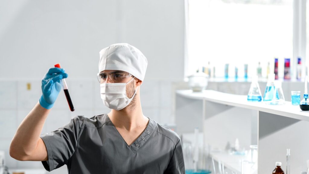 A laboratory worker holding a blood sample tube.