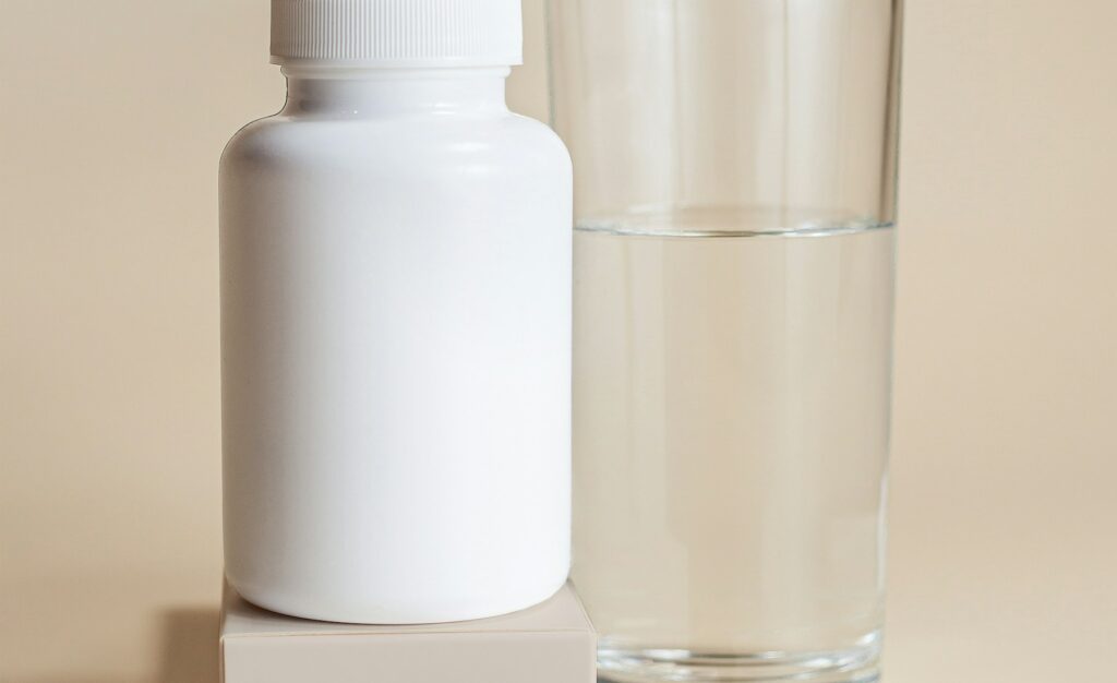 Unbranded supplement container beside a glass of water; illustrative image, not an identified iron product