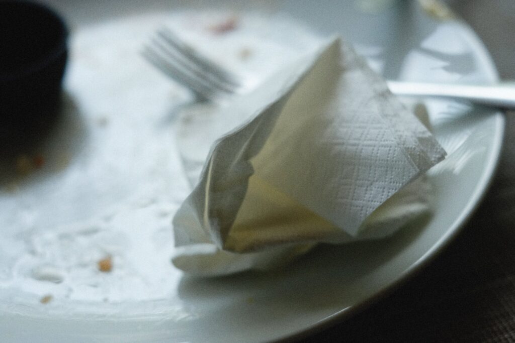 An empty plate with a napkin and fork on a table.