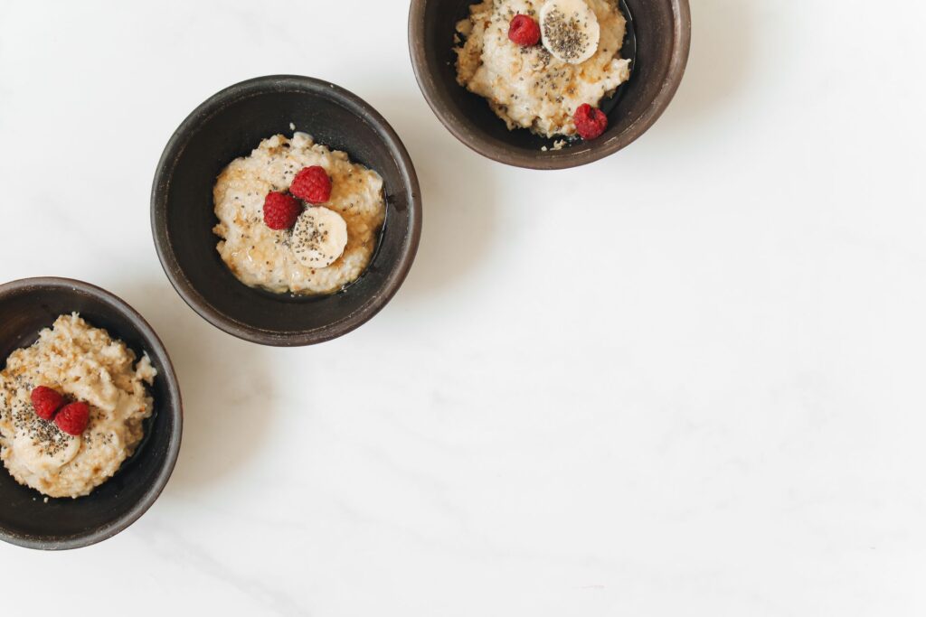 Bowls of porridge topped with banana, raspberries and seeds.